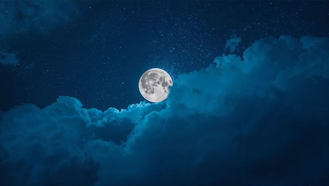 Luminous Full Moon Glowing Above Cloudy Night Sky