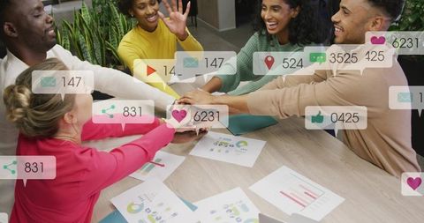 Team stacking hands over analytics reports with social media engagement overlays