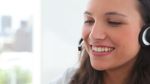 Professional Woman Smiling While Using Headset in Office