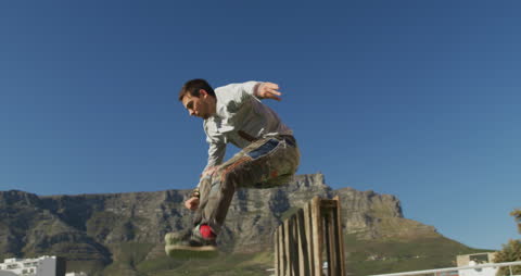 Man Practicing Parkour on Rooftop Against Mountainous Backdrop