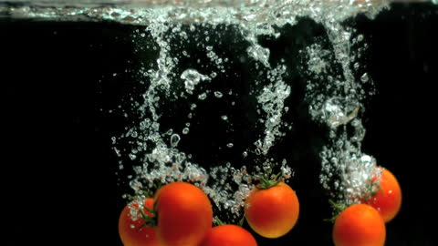 Juicy Red Tomatoes Splashing into Water with Bubbles