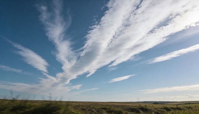 Stretching streaking cirrus clouds across open grassland horizon pastoral panorama