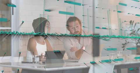 Collaborating coworkers pointing at tablet with turquoise 3d data overlay in modern office