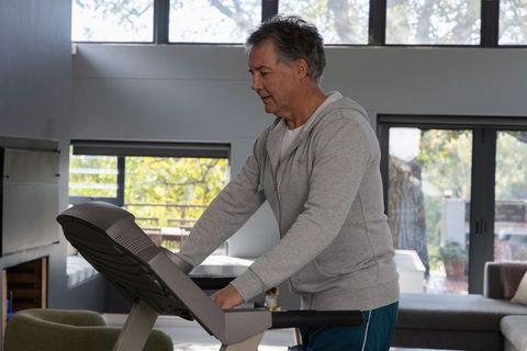 Senior Man Exercising on Treadmill in Sunlit Modern Living Room