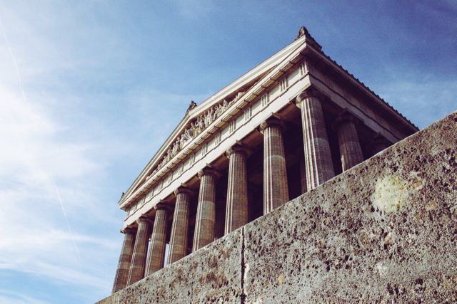 Ancient Greek temple with iconic columns against clear blue sky. Useful for illustrating ancient architecture, history lessons, Greek culture, travel destinations, and archaeological studies.
