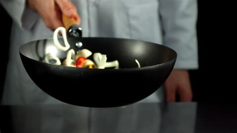 Chef Tossing Vegetables in Wok with Skillful Motion
