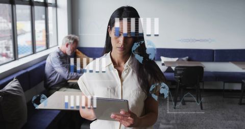 Biracial businesswoman using tablet with financial data overlay in modern office