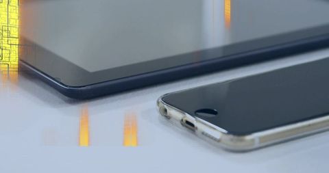 Smartphone in clear case resting beside tablet showing glossy home button and reflections