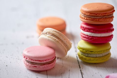 Colorful French macarons stacked and scattered on rustic white wooden surface