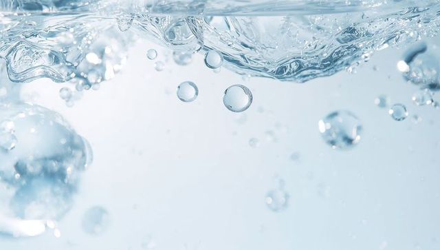 Rising water bubbles beneath rippling surface in crystal clear liquid purity concept