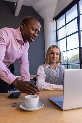 Focused Coworkers Collaborating in Modern Office with Laptop and Coffee