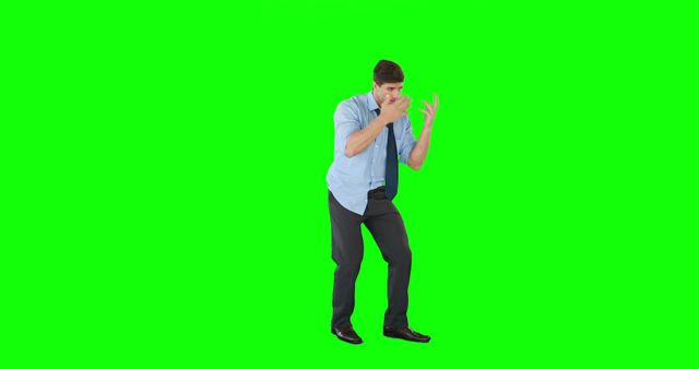A young Caucasian businessman appears startled or defensive against a green screen background, with copy space. His body language suggests surprise or a reaction to an unexpected situation.