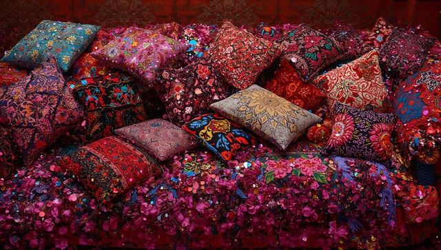 Bohemian jewel-toned embroidered pillows piled on sequined velvet daybed with tassels
