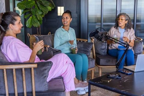 Women recording wellness podcast while sipping green smoothies in relaxed lounge