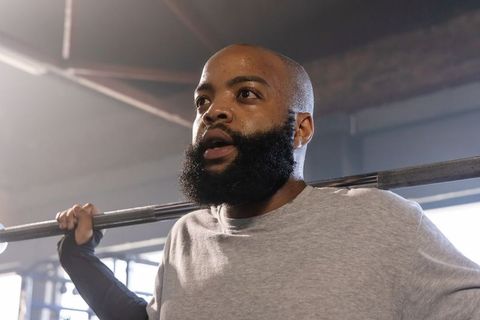 African american man performing heavy squat with spotter in gym strength training focus