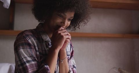 Smiling woman with afro hair enjoying digital interaction indoors