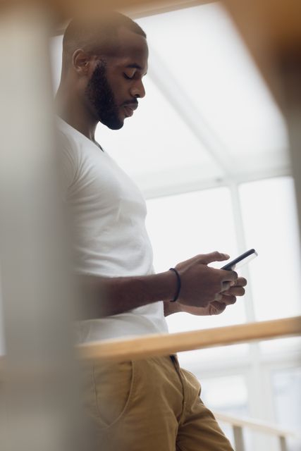 Side view of an African-American using a smartphone inside a white room