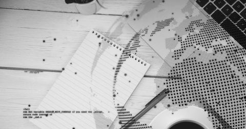 Monochrome workspace with notebook, laptop, pen and halftone world map overlay