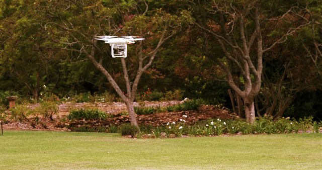 Drone flying over a well-maintained garden in a green park. The trees and plants in the background create a serene and natural atmosphere ideal for relaxation and tranquility. Suitable for technology ads, nature themes, aerial photography catalogs, and marketing materials focused on innovative gadgets.