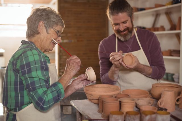 Male and female potter painting pots in pottery workshop