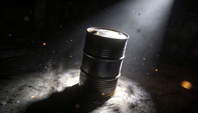 Dented Rusted Steel Barrel Spotlighted on Concrete Floor with Flying Sparks and Dust