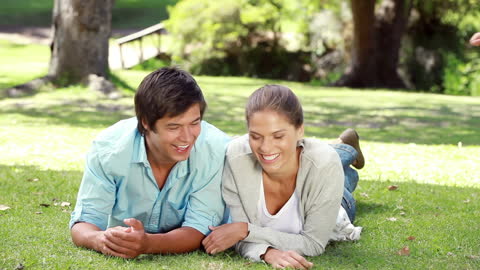 Happy Couple Relaxing on Grass in Sunny Park
