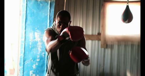 Determined African American Boxer Punching in Fitness Studio