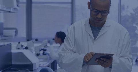 Reviewing scientist using tablet in modern laboratory with microscopes and lab equipment