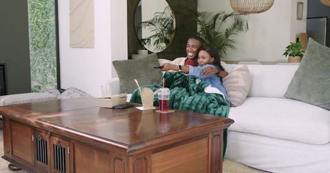 Couple relaxing on sofa sharing takeout and watching tv