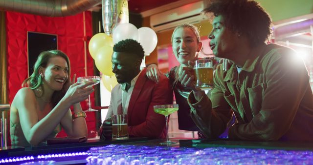 Image of diverse group of happy friends standing at the bar drinking and talking at a nightclub. Friendship, going out and socialising concept.