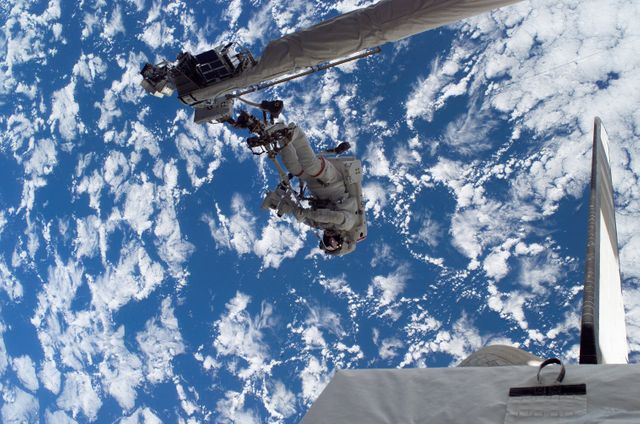 Astronaut performing a critical space operation during the STS-121 mission. An iconic image showing the vastness of Earth below and the intricacies of space missions. Ideal for use in educational materials, science exhibits, space exploration features, and NASA mission documentation.