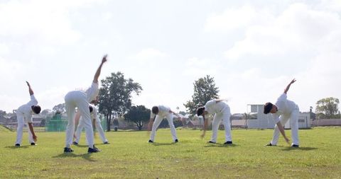 Cricket team warming up with side stretches on field