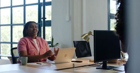 African woman speaking and gesturing during collaborative meeting in bright modern open-plan office