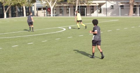 Teenagers Playing Soccer on Sunny School Field