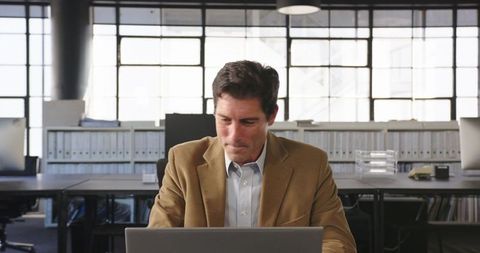 Businessman Celebrating Success with Laptop in Modern Office