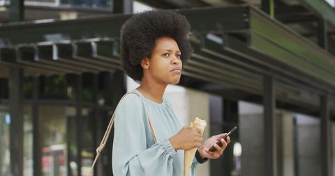 Businesswoman Eating Lunch While Using Smartphone Outdoors