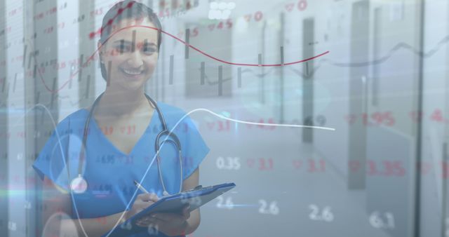 Smiling female doctor in blue scrubs analyzing healthcare data and trends with digital graphs and charts overlayed. Useful for content about medical professions, healthcare technology, data analysis in medicine, and medical research.