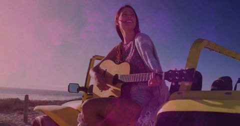 Bohemian woman playing guitar on a coastal road adventure