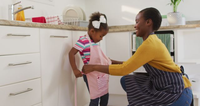 Mother Helping Daughter With Apron in Kitchen - Download Free Stock Images Pikwizard.com