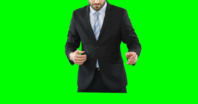 A Caucasian businessman in a suit is posing against a green screen, with copy space. His stance suggests confidence and readiness, ideal for professional or corporate themes.