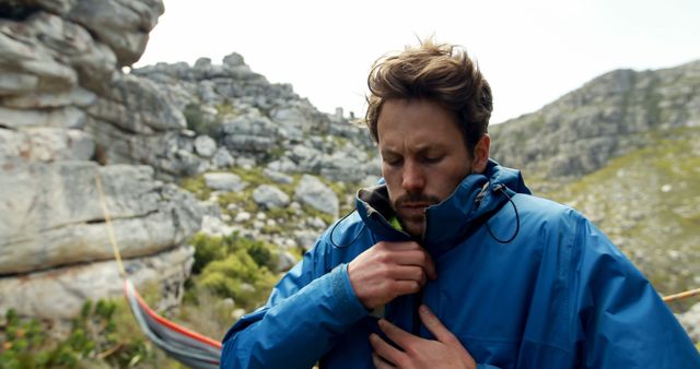 Man zipping jacket while hiking in rocky landscape - Download Free Stock Images Pikwizard.com