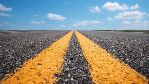 Low-angle double yellow lines leading toward horizon on open rural road