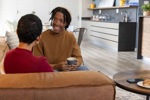 African american friends chatting on sofa in cozy modern open-plan kitchen