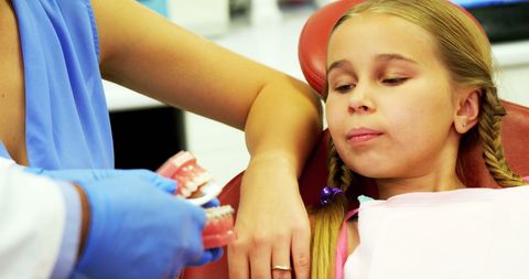 Dentist educating young patient on brushing techniques