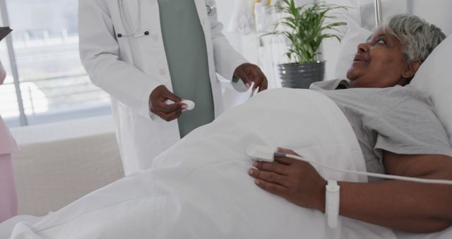 A senior woman lies in a hospital bed while a doctor in a white coat attends to her. This image can be used for medical and healthcare-related content, promoting hospital services, illustrating patient care programs, or in educational materials related to elderly care and healthcare practices.