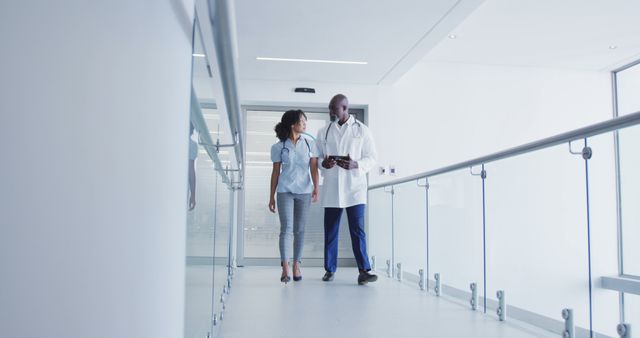 Medical professionals walking and conversing in a bright and modern hospital corridor. This can be used for healthcare websites, medical brochure designs, hospital-based articles, or wellness blogs that highlight professional interactions and healthcare environments.