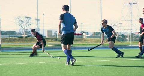 Athletes Competing in Intense Field Hockey Match on Synthetic Turf
