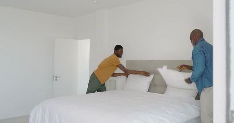 Father and son making bed creating comfort in minimalist bedroom