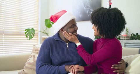 African American Couple Sharing Warm Holiday Moment on Couch with Santa Hat