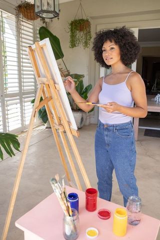African American Artist Painting on Canvas in Bright Studio